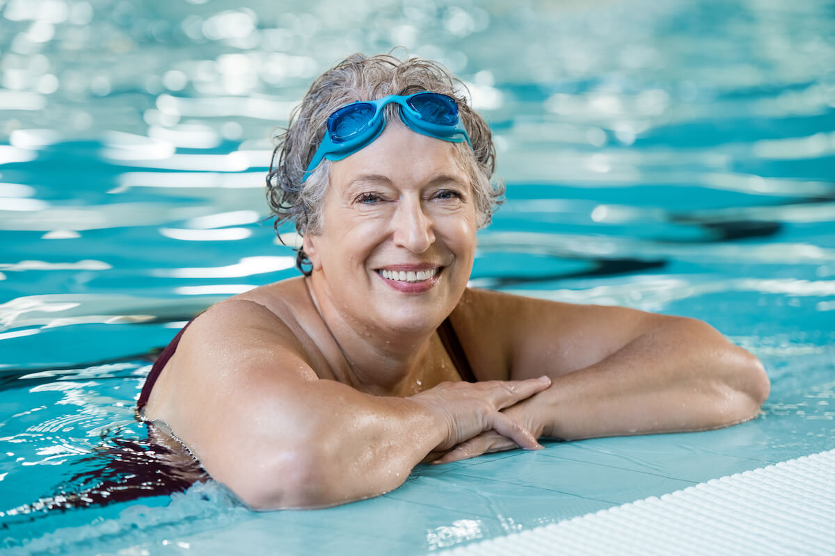 Mature woman wearing swim goggles at swimming pool