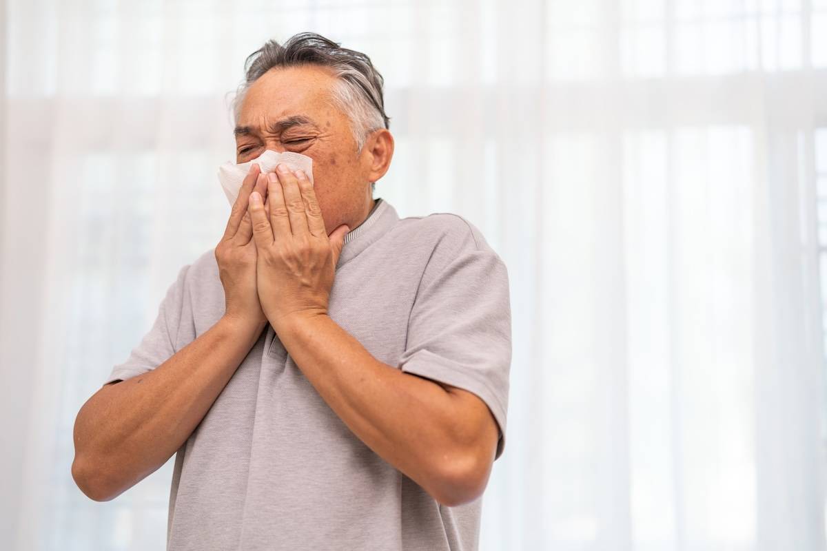 Senior asian man sneezing into a tissue, experiencing discomfort from cold or allergies, seasonal allergies, virus, flu and sick health, wellness, senior care, and medical treatment for respiratory Common Seasonal Illnesses